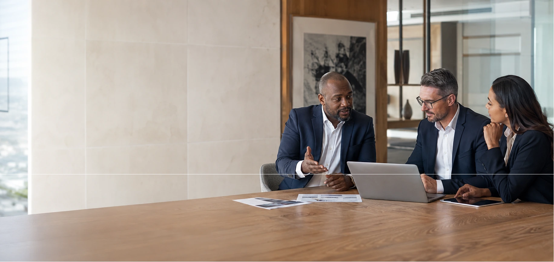 Three business professionals working together around a laptop